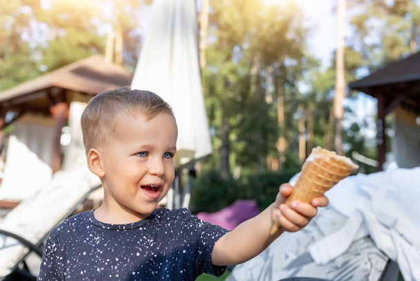 Little cute adorable playful caucasian blond toddler boy kid sharing sweet tasty ice cream with mom on hot summer day outdoors. Two happy people enjoy dessert during vacation holidays together - Фото, изображение