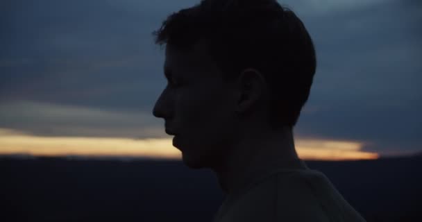 Close-up zicht op een mannelijke reiziger op de top van de heuvel rond te kijken naar het panoramische uitzicht tijdens de zonsondergang. - Video