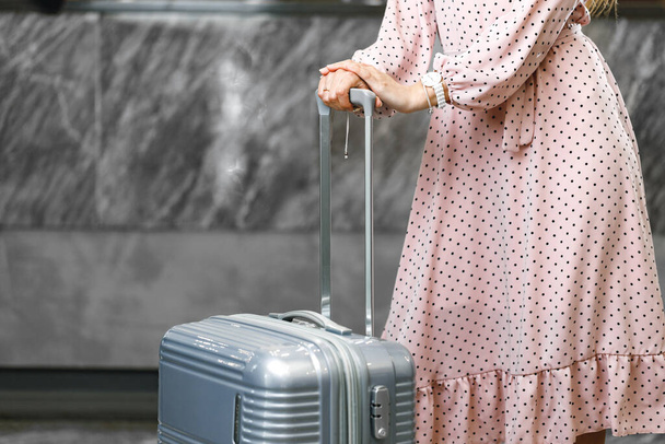 Unrecognizable woman in pink dress standing with luggage suitcase - Fotografie, Obrázek