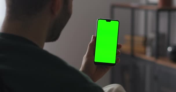 άντρας χρήστης χαιρετάει φίλους ή συναδέλφους με online chat στο smartphone, χαιρετώντας το χέρι, να πω γεια, πράσινη οθόνη στο gadget για chromakey - Πλάνα, βίντεο