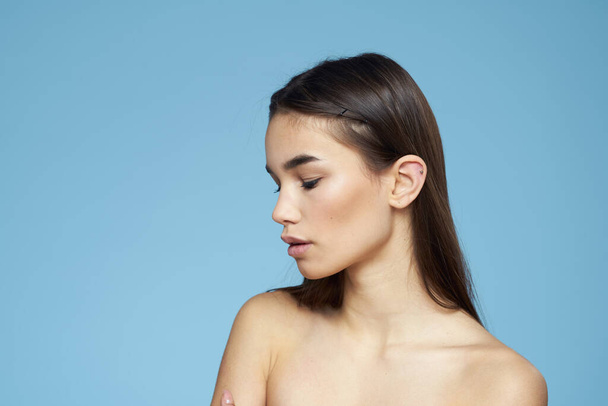 brunette with bare shoulders cosmetics close-up skin care blue background - Photo, Image