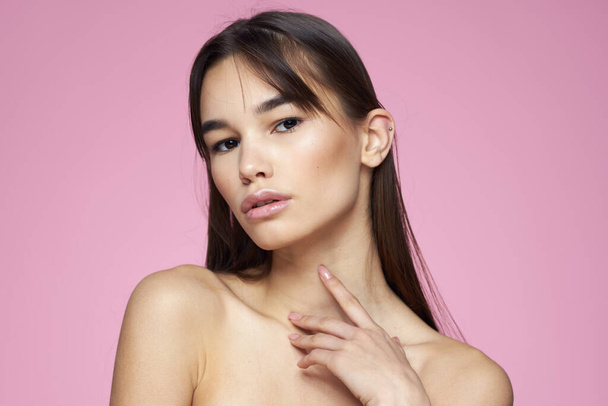 Vrouw met blote schouders haarverzorging make-up schone huid roze achtergrond - Foto, afbeelding