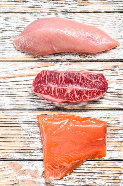 https://cdn.create.vista.com/api/media/small/448911464/stock-photo-three-types-of-steaks-on-wooden-table-beef-top-blade-salmon-fillet-and-turkey-breast