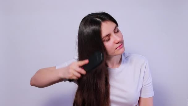 La chica sostiene un cepillo de pelo con el pelo cayéndose, peinando y gritando. Pérdida de cabello, cuidado del cabello. - Metraje, vídeo