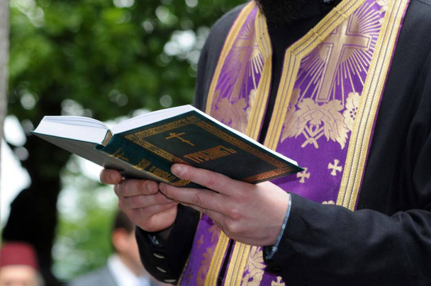 священник восточной православной церкви проводит церемонию на открытом воздухе - Фото, изображение