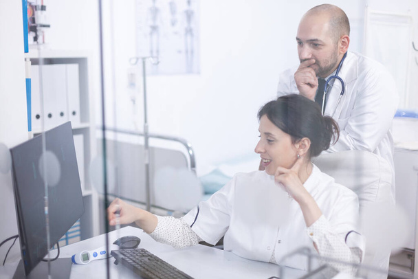 Jeune couple de médecins analysant le scan médical sur ordinateur - Photo, image