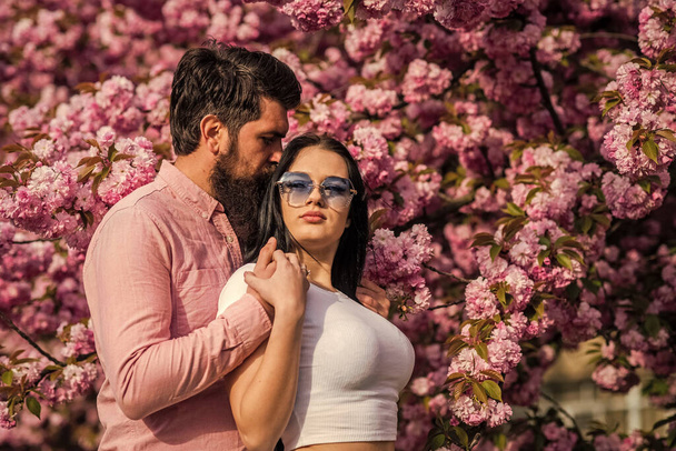 Modisches Paar auf Frühlingshintergrund. Verliebte Paare genießen die rosa Kirschblüte. Mann und Frau im blühenden Garten. Frohe Ostern. Verliebte Paare blühen auf. Mann und Frau in Kirschblüte - Foto, Bild