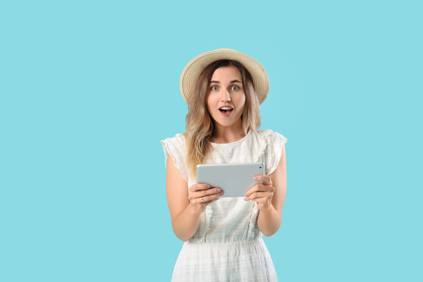 Mujer joven sorprendida con el ordenador tableta en el fondo de color - Foto, imagen