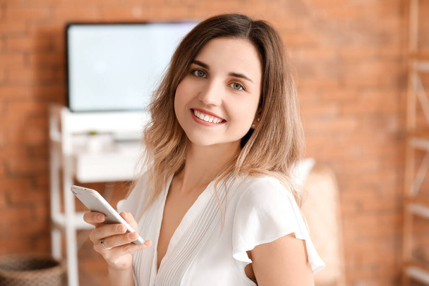 Young woman with mobile phone in office - Photo, image