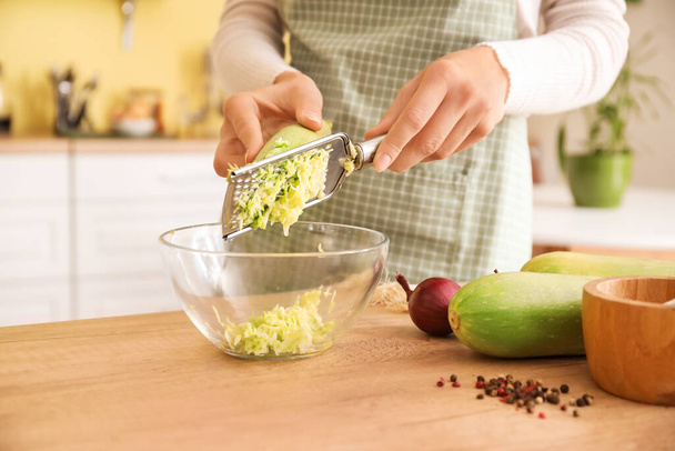Donna grattugia zucchine in cucina - Foto, immagini