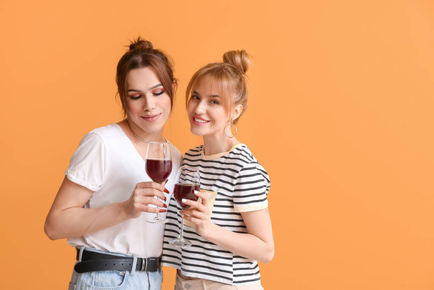 Young transgender couple with glasses of wine on color background. Valentine's Day celebration - Foto, afbeelding