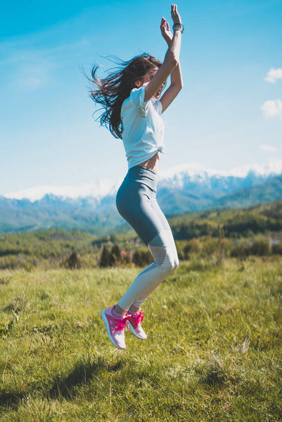 Happy Carefree menina saltando alto ao ar livre com montanhas nevadas e céu azul no fundo - Foto, Imagem