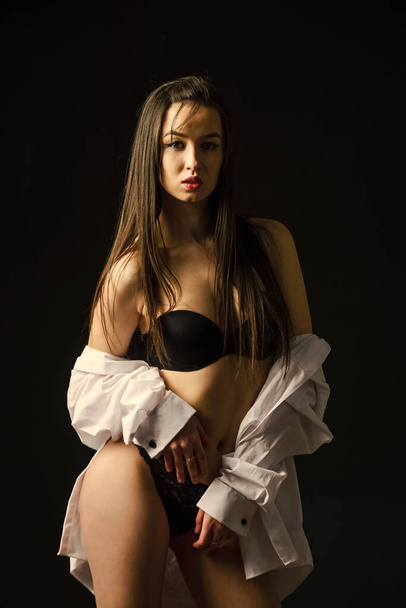 Feeling flirty tonight. sexy woman wear erotic lingerie and shirt. sensual girl in male shirt. beauty and fashion. woman has fit and slim body. sensual female isolated on black. express her sexuality - 写真・画像