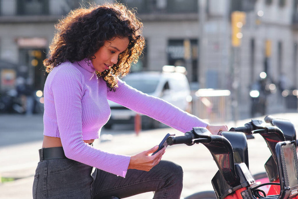 Femme utilisant l'application de téléphone mobile pour louer un vélo. - Photo, image