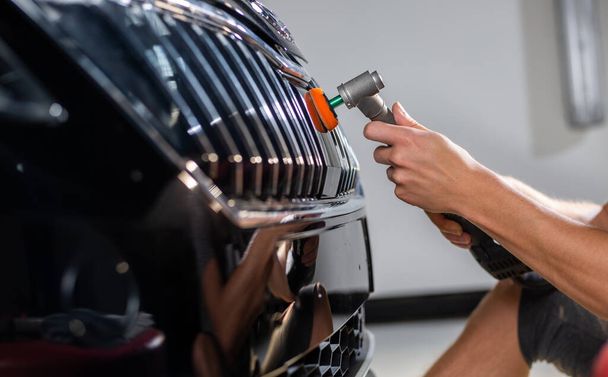 Close-up van auto detailist handen, schoonmaken of pilishing van de auto door poliermaschine, auto detaillering concept - Foto, afbeelding
