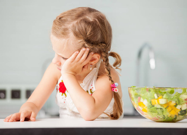 Little girl refuses to eat salad. Child looks with disgust for food - Foto, Imagem