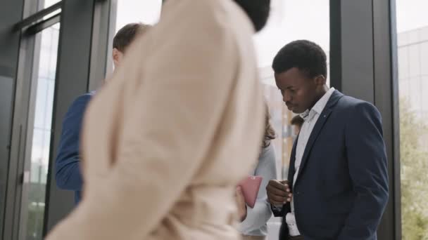 Średnie ujęcie dwóch różnych biznesmenów i biznesmenki mieszanej rasy stojącej w centrum biznesowym, patrzącej na cyfrową kobietę z ekranem tabletu trzymającą się za ręce i mającą dyskusję - Materiał filmowy, wideo