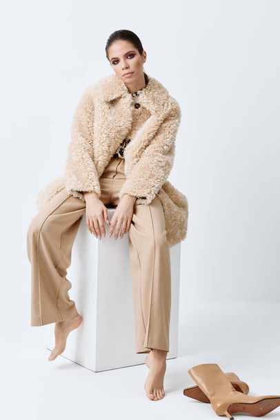 brunetta con trucco luminoso sul suo viso cappotto beige vestiti alla moda - Foto, immagini