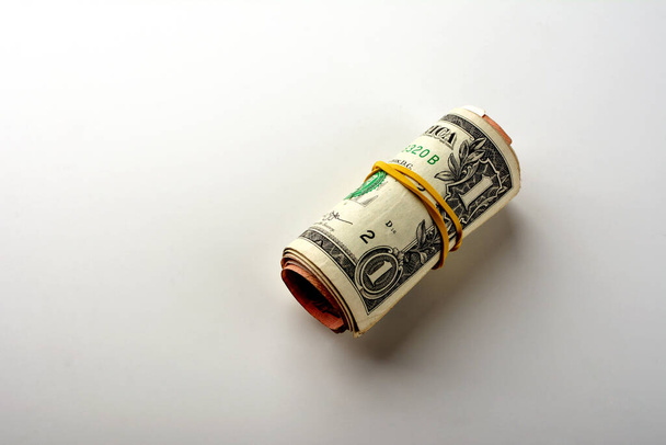 One and two dollars rolled into a tube on a white background. - Фото, изображение