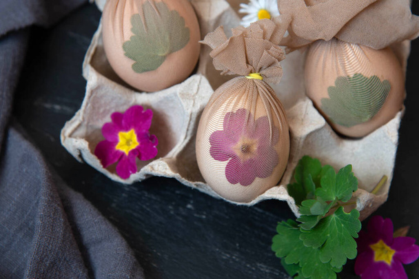 Preparación de huevos de Pascua antes de pintar con un patrón de hierbas frescas, flores. - Foto, imagen