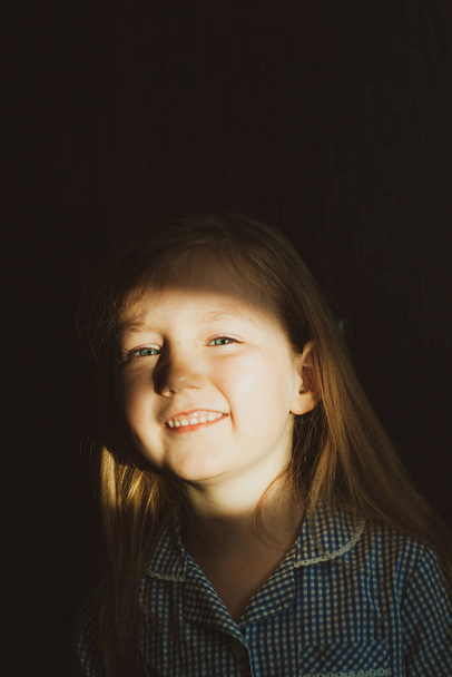 Pieni nätti tyttö hymyilee aurinkoinen pupu kasvoillaan. Söpö sinisilmäinen lapsi nauraa. Pitkät vaaleat hiukset. Vintage linssi lapset kotiin muotokuva päivänvalossa. Kasvaminen psykologia henkilökohtainen kehitys. - Valokuva, kuva