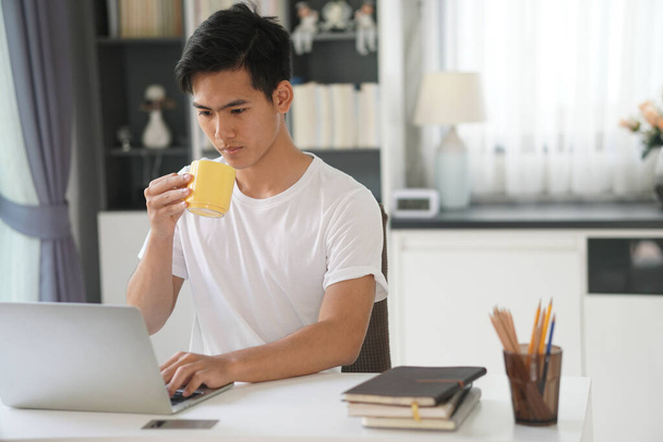 aziatische jonge tiener student man tiener ondernemer werken met computer studeren online thuis. e-learning webinar bijeenkomst. sociale afstand bij hevige pandemie - Foto, afbeelding