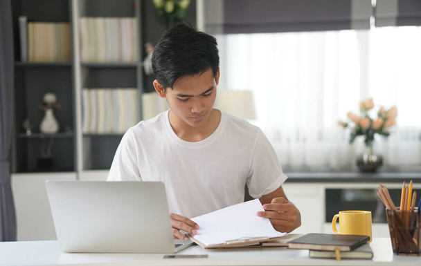 azjatycki młody student człowiek nastolatek przedsiębiorca pracuje z komputerem studiuje naukę online w domu. Spotkanie webinarne e-learningowe. odległość społeczna w pandemii rzekomej - Zdjęcie, obraz