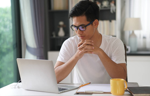 ázsiai fiatal tizenéves diák férfi tizenéves vállalkozó dolgozik számítógép tanul online otthon. e-learning webinar találkozó. társadalmi távolság kovid világjárvány esetén - Fotó, kép