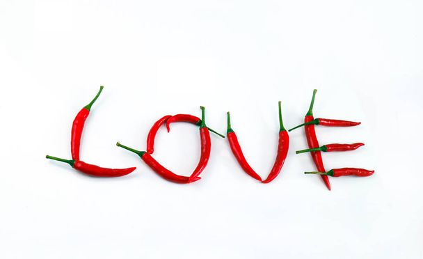 písmo láska napsaná chilli paprikou na bílém pozadí, skupina červené chilli, horní pohled,  - Fotografie, Obrázek