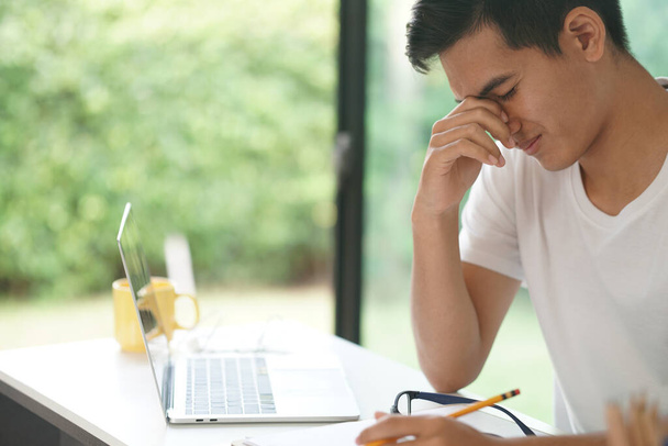 Mladý asijský teenager student muž teenager podnikatel studující tvrdě pracovat pocit únavy unuděný znuděný. pracovní výchova doma - Fotografie, Obrázek