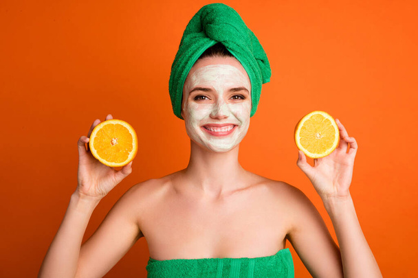 Photo of toothy beaming woman girl wear green turban smiling applying fruit soap face isolated orange color background - Foto, immagini