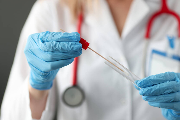 Doctor wearing gloves inserting cotton swab into test tube closeup - Foto, Bild