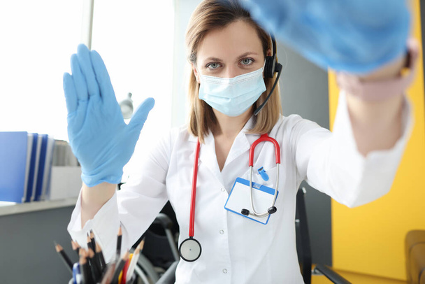 Врач в маске и перчатках приветствует пациента на экране монитора - Фото, изображение