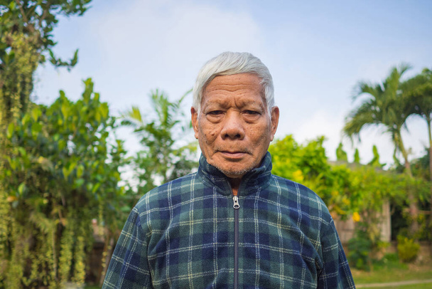 Retrato de un anciano asiático sonriendo y mirando a la cámara mientras estaba de pie en un jardín. Espacio para el texto. Concepto de personas mayores y asistencia sanitaria. - Foto, Imagen