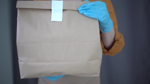 gezondheidsbescherming, veiligheid en pandemie concept - levering vrouw in het gezicht beschermende masker en handschoenen met pakket doos en over magazijn achtergrond - Video