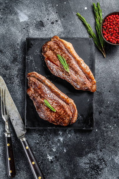 Grilovaná vrchní svíčková nebo pikanha steak na kamenné sekačce. Černé pozadí. Horní pohled - Fotografie, Obrázek
