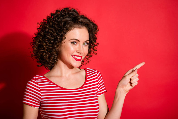 Photo of pretty lovely curly young lady wear casual striped outfit pointing empty space isolated red color background - Valokuva, kuva