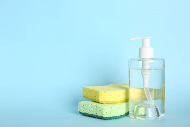Cleaning product and sponges on light blue background, space for text. Dish washing supplies - Φωτογραφία, εικόνα