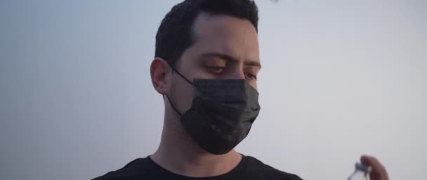 A man wearing a black mask holding a bottle of Vaccine and looking up - Footage, Video