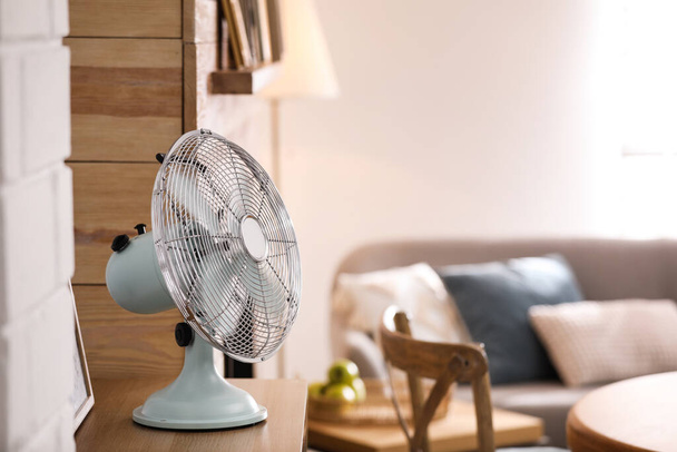 Modern electric fan on wooden table in living room. Space for text - Фото, изображение