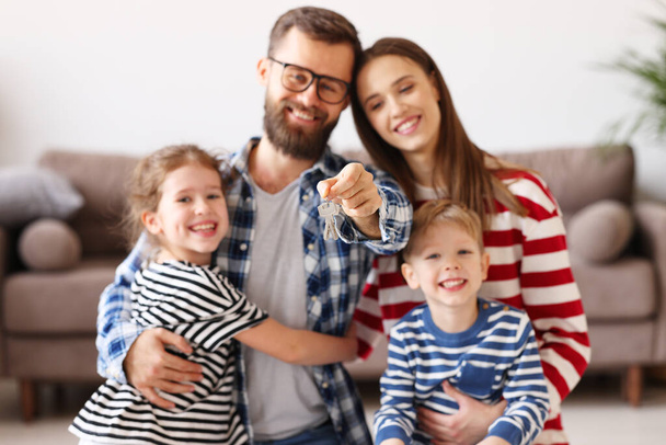 Soft focus of cheerful parents and kids hugging and showing keys of new flat to camera - Photo, Image