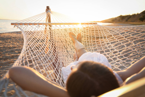 Young woman relaxing in hammock on beach at sunset, closeup - 写真・画像