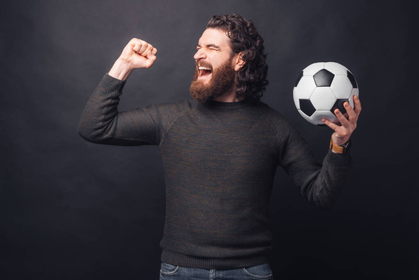 Портрет изумленного красивого бородатого мужчины в случайном захвате футбольного мяча и праздновании победы - Фото, изображение