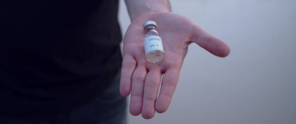 Une main ouverte saisit fermement la bouteille de vaccin covide 19 au ralenti  - Séquence, vidéo