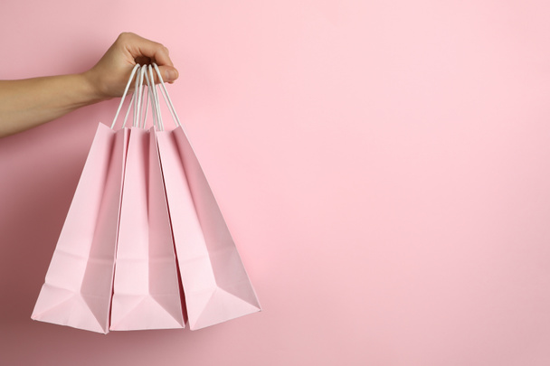 Female hand hold shop bags on pink background - Photo, Image