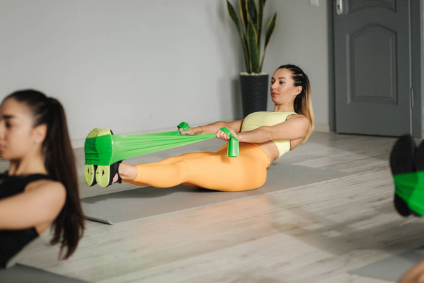 Group of young sporty attractive woman practicing pilates. People standing together. Working out, indoor full length, studio background - Фото, зображення