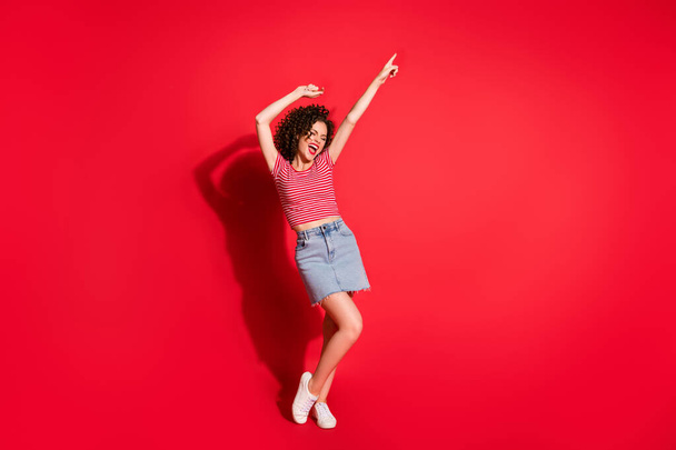 Full body photo of young positive girl enjoy point finger empty space yell shout wear mini skirt isolated over red color background - Foto, immagini