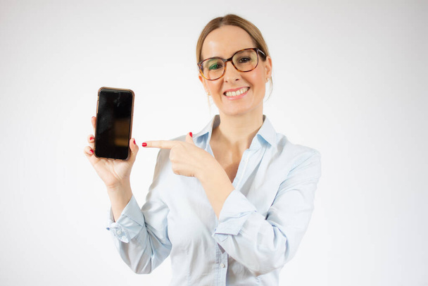 Νεαρή επιχειρηματίας δείχνει έξυπνο τηλέφωνο πάνω από λευκό φόντο. - Φωτογραφία, εικόνα