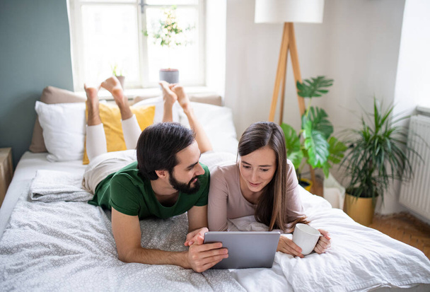 Young couple in love using tablet on bed indoors at home. - Фото, зображення