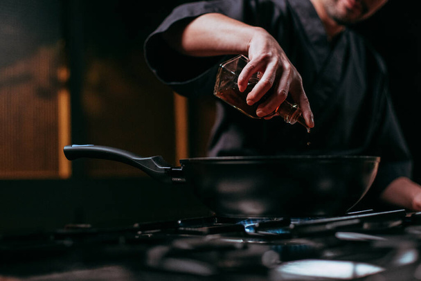 nerozpoznatelný kuchař nalévá olej do pánve - Fotografie, Obrázek